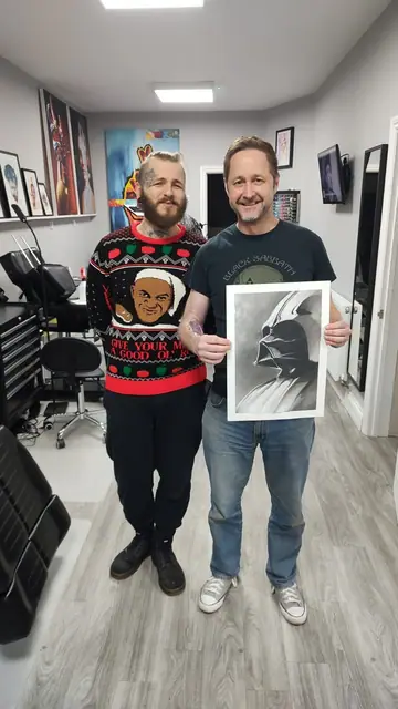 black and grey darth vader drawing held by client with artist
