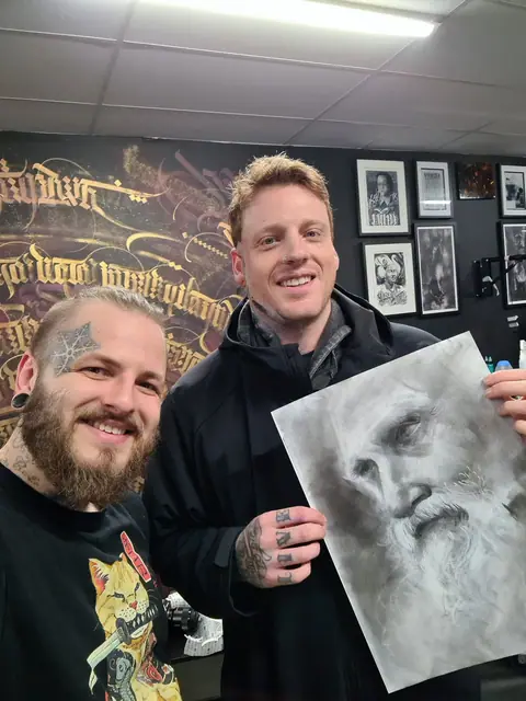 two men holding a black and white portrait drawing