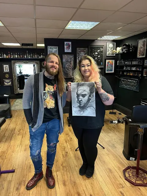 two people posing with a black and grey frankenstein drawing