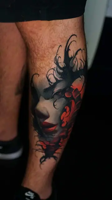 abstract portrait tattoo with red accents on calf