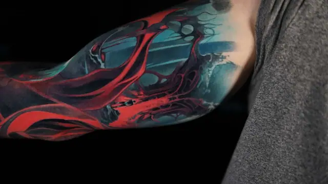 abstract red and blue biomechanical full-sleeve tattoo on arm
