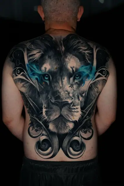 black and grey lion with blue eyes tattooed across a full back