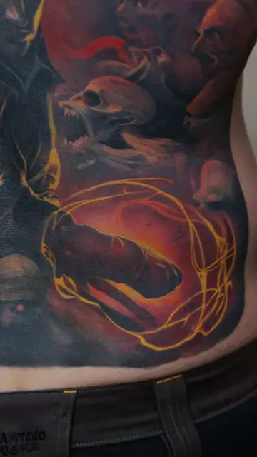 colour realism demon faces and swirling energy tattoo on lower back/hip