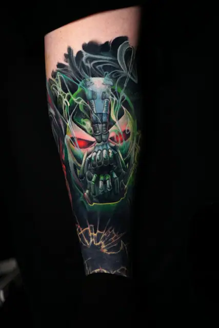 colour realism stylized bane skull tattoo with green smoke on forearm