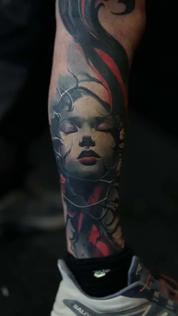 colour realism woman's face tattoo on lower leg