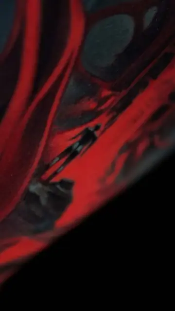 red and black abstract figure tattoo on arm