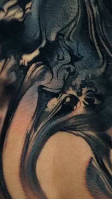 abstract black and grey flowing tattoo on skin close up