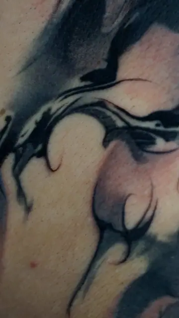 abstract black and grey swirl tattoo on skin