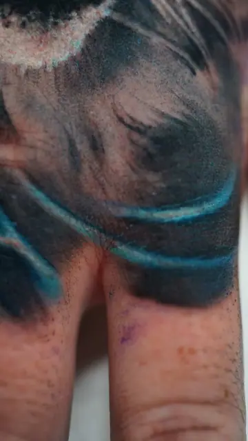 abstract blue and black tattoo on hand knuckles