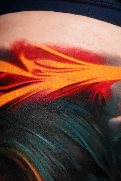 close-up detail of orange and teal abstract flowing tattoo
