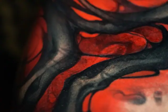 abstract red and black flowing tattoo design on skin