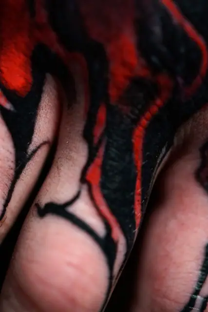 abstract red and black tattoo on hand and fingers
