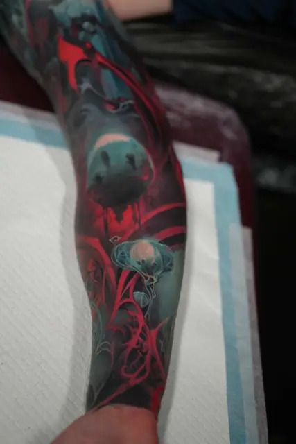 bioluminescent creature and jellyfish colour realism tattoo on arm