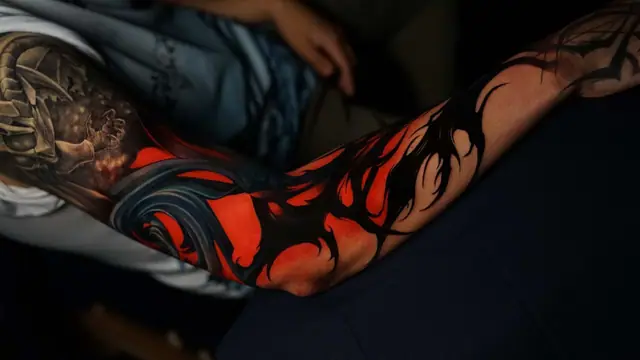 biomechanical tribal full sleeve tattoo with red and black accents