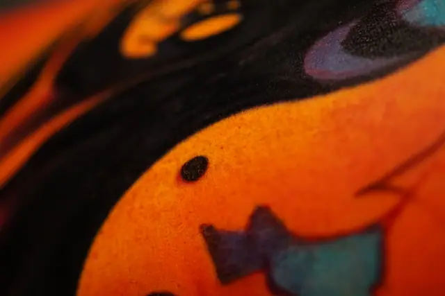 colorful abstract tattoo close-up, orange, black, and teal colors