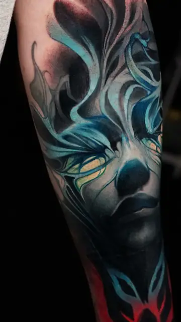 colour realism abstract face tattoo with blue highlights on forearm