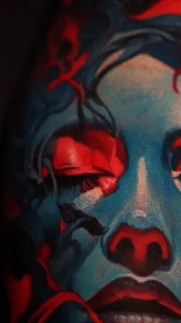 colour realism blue woman face tattoo with red accents on arm