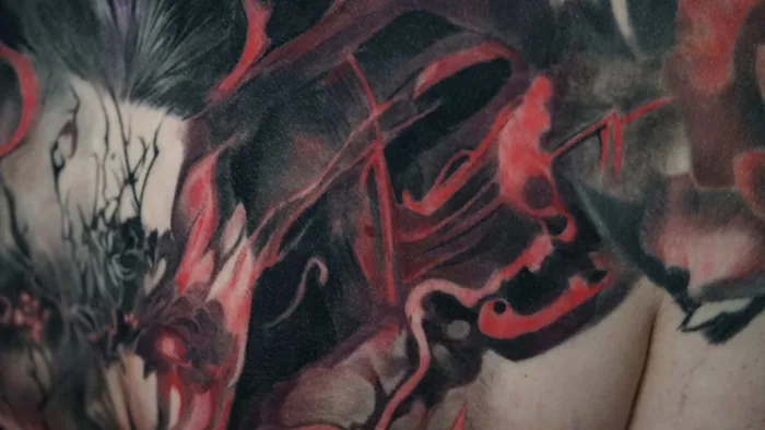 close-up detail of red and black demon back tattoo