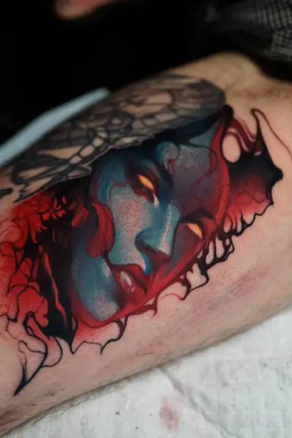 colour realism demoness face tattoo with red elements on leg