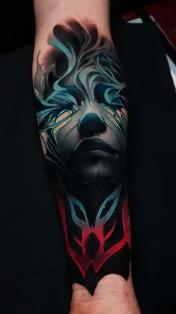 colour realism ethereal face tattoo with abstract glow on forearm