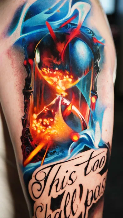 close-up of hourglass tattoo with 'this too shall pass' lettering