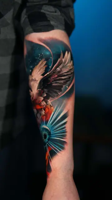 colour realism winged bird and eye tattoo on forearm