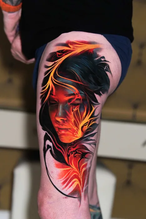 colour realism woman's face in fire and smoke tattoo on thigh