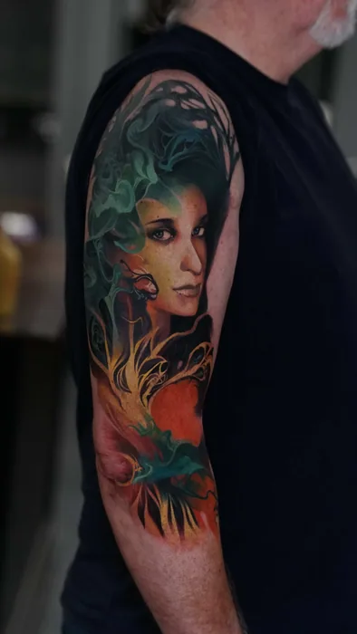colour realism woman's face with teal foliage tattoo on upper arm