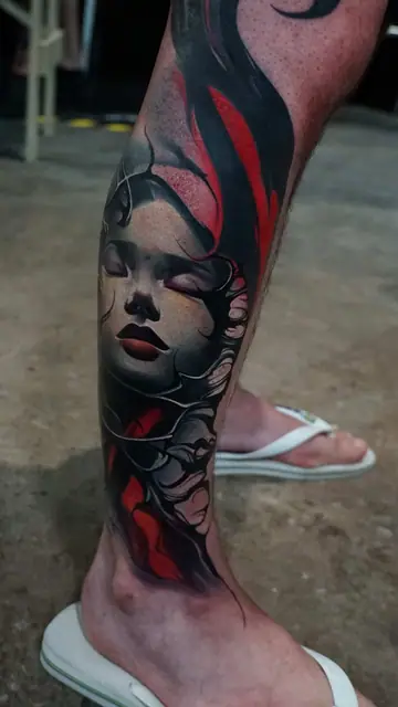 colour realism woman's face and abstract shapes tattoo on lower leg