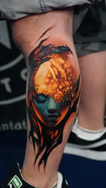 colour realism woman's face with glowing head tattoo on lower leg