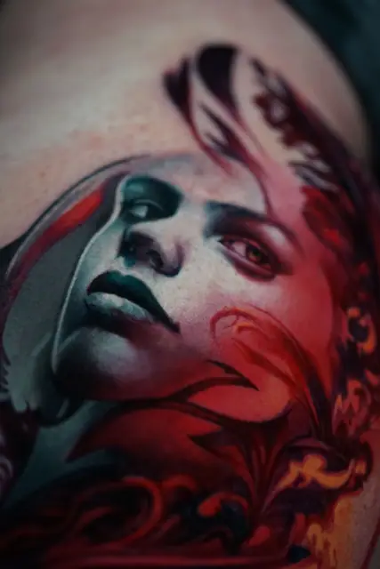 colour realism woman's portrait tattoo with red accents on skin