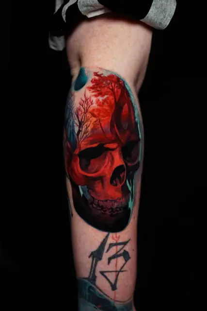 colour realistic skull and forest tattoo on leg