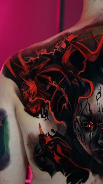 dark evil face tattoo with red accents on chest and shoulder