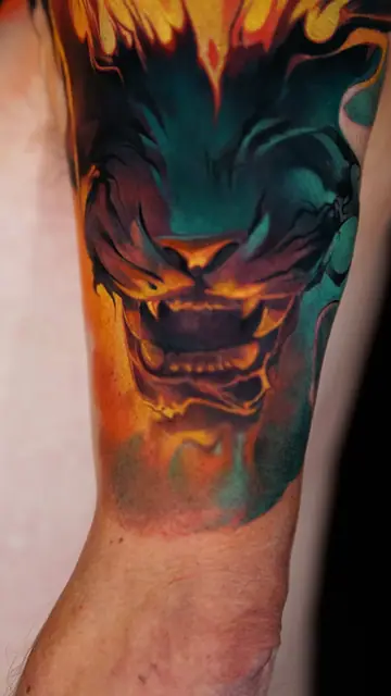 flaming stylized beast head tattoo on forearm