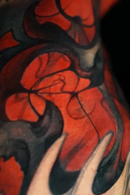 red and black abstract organic design tattoo on skin