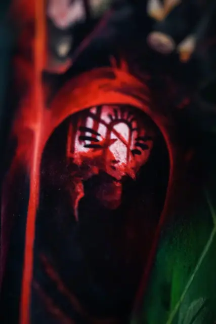 red hooded dark figure colour tattoo, possibly on arm